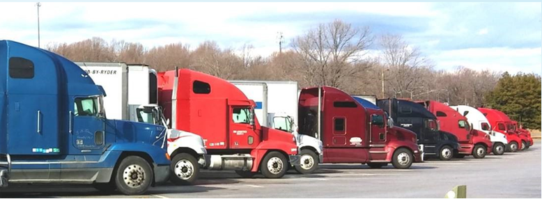 Sdie view of a number of freight trucks parked.