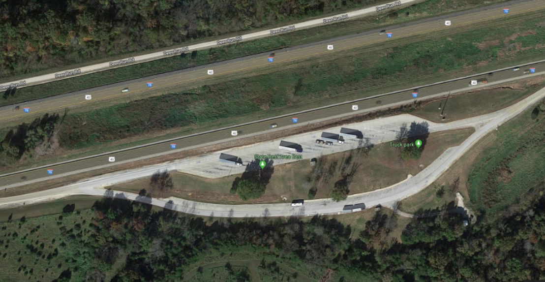 Aerial view of trucks parked in a former highway rest area.