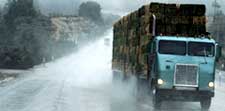 A high-profile vehicle on a road during high winds and rain.