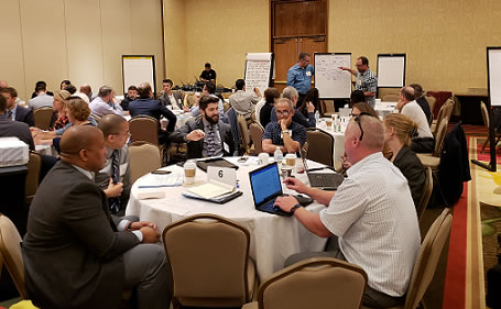 Image of group session with people talking around tables.