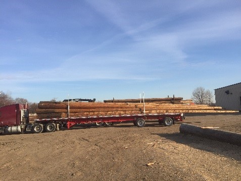 A red flatbed truck hauling utility poles.