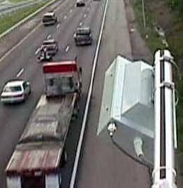 photo of an acoustic array sensor mounted above and to the side of three lanes of one direction of a highway with vehicles moving past the sensor