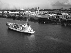 Aerial view of a container ship leaving a port facility and container yard.