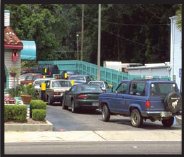 Photograph of vehicles at a fast-food restaurant overflowing the drive-through lane and backed up into the roadway.