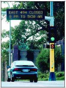 A changeable message sign above a light indicating a road closure during overnight hours.