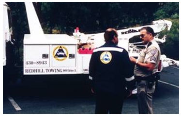 Photograph of two first responders in front of a CALTRANS freeway patrol vehicle with tow capability.