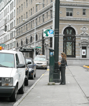 Photo of a woman using a card in a parking meter.