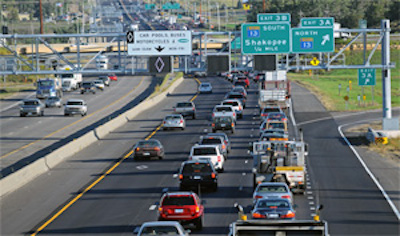 Picture of Active Traffic Management signage in Minneapolis with a dynamic message sign showing that the left lane is for HOV (via the diamond). Dynamic message signs are also installed over the other two lanes for indicating speed advisories or lane assignment information.