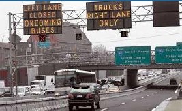 Picture of reversible lane, with left lane along a freeway closed to accommodate buses travelling in the opposite direction.