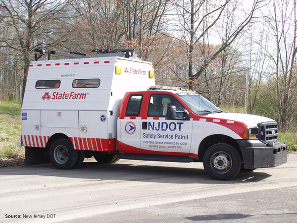 Photo of a NJDOT safety service patrol vehicle. The truck is painted white and red, has emergency lights and is fitted with a large storage compartment.