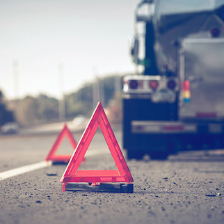 [photo 4]. This photo shows roadway hazard triangles with a truck in the background stalled on the roadway shoulder.