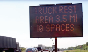 A permanent dynamic message sign mounted near a roadway displays traveler information to drivers.