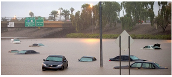 Deeply flooded roadway between two embankments at an underpass with cars almost completely under water.