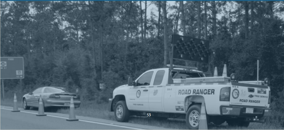 A traffic work truck with mounted led sign on top is parked beside road with orange cones.