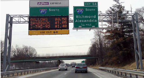 A dynamic sign mounted on a gantry depicts the cost to travel to different destinations.