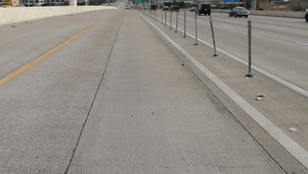 Figure 9. Graphic. Photo from a driver perspective of the buffer markings along with vertical pylons used to separate a managed lane from a general-purpose lane. The markings consist of two solid white lines. The separation between the two solid white lines is about 5 ft.