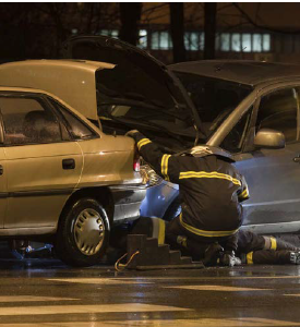 Two first responders at the scene of a crash working to clear two wrecked vehicles.