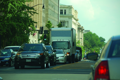 Busy street in city traffic with a large delivery truck in the center of picture.