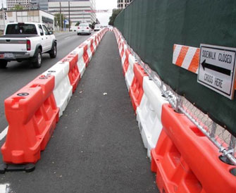 This photo shows longitudinal channelizing devices arranged to delineate a pedestrian walkway on the far right side of a street.