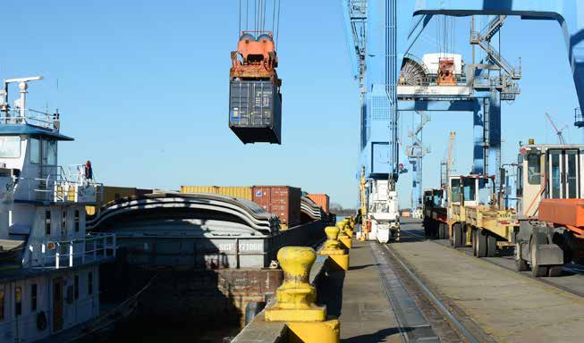 photo of a shipping container hoisted above a barge by a crane