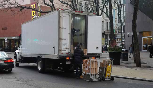 photo of a worker unloading a delivery truck parked on a city street