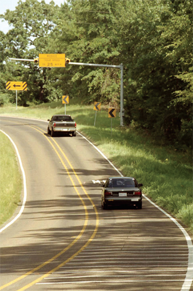 Vehicles traveling along a curved rural road.