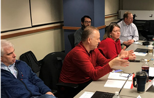 A group of people sitting around a table in a discussion group.