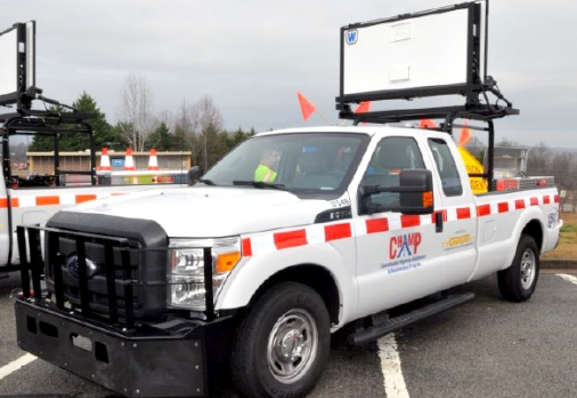 Side view of a pickup truck equipped with a message board and other roadway assistance equipment in the bed and with the CHAMP logo on the driver's side door.