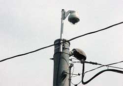 photo showing a closed-circuit television camera mounted to the top of a traffic signal pole