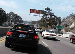 photo showing a changeable message sign, located over a multi-lane roadway, displaying permitted turning movements for each lane at a downstream intersection