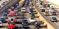Busy Interstate with many lanes of traffic going both ways.