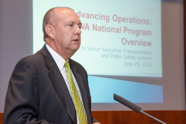 Photograph of Jeff Lindley at the dais, in front of a projection screen of his presentation