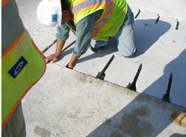 A slab using where a pre-drill procedure has been applied. Dowels are predrilled and epoxied into adjacent slabs and then the precast slab with preformed slots on the underside is placed within the opening and the dowel slots grouted through port holes on the top of each slab.