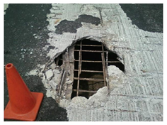 A badly degraded bridge deck with steel beams and rebar exposed through surface holes.