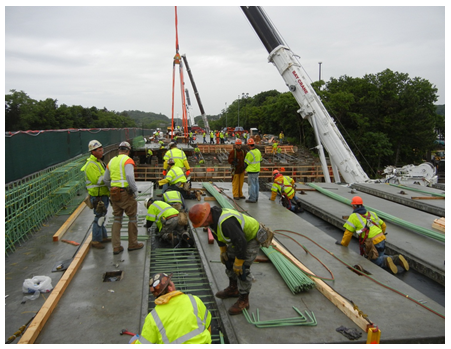 Workers working to anchor the newly placed modular units.