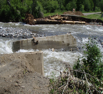 A rushing creek where a bridge has been washed out.