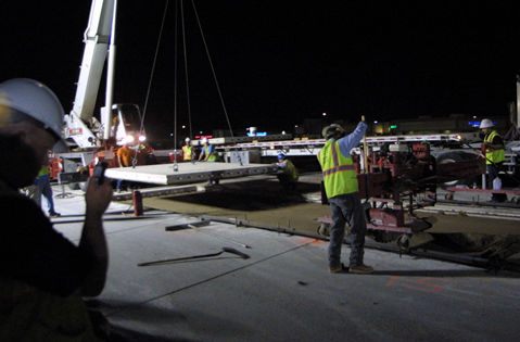 Workmen installing precast slabs at night.