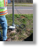 A worker next to a road tube traffic counter.