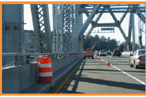 a construction barrel on the left side of a bridge