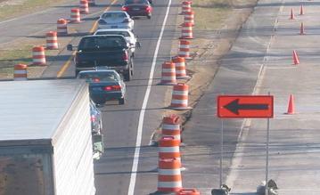 Photo of cars and trucks being redirected from a closed portion of the highway by channelizing drums