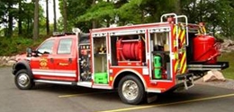 Photo of a red work truck with its side panels open to expose the work zone and other safety equipment stored in side compartments.