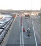 Aerial photograph of a work zone with the exit ramp closed and blocked by an attenuator in front of a cement barrier. A DMS sign indicates the road is closed.