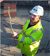 Photo of a worker wearing a yellow-green safety jacket and a hard hat bearing the New Hampshire DOT logo.