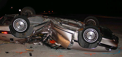 Photo of a crashed car flipped onto its roof.