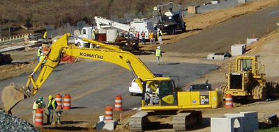 work crews with backhoes paving a road