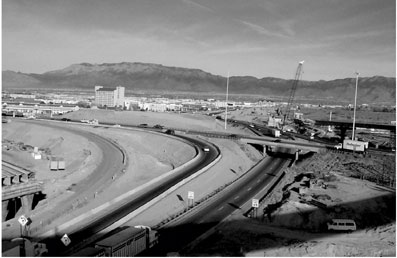 The cover photo shows the Big I interchange under construction. Traffic is flowing on a number of ramps. A construction crane is shown in the background constructing a bridge. A partially constructed bridge is shown in the foreground.