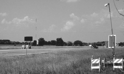 Figure 2 shows a stretch of I-55 upstream from the construction zone flanked by a traffic sensor suspended approximately 20 feet off the ground on a boom attached to a trailer equipped with a solar array in the right foreground. There is a portable DMS in the left midground on the other side of the highway. A single car is seen passing the sensor.