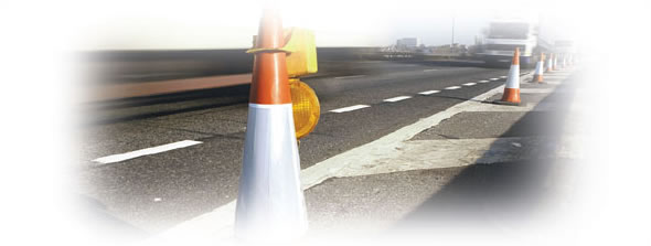 Photograph taken at road-level of placed along a stretch of road.  A truck is in the foreground driving in the open lane.