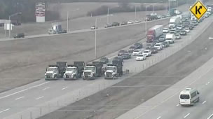 Four work trucks side by side block the interstate in a rolling roadblock.